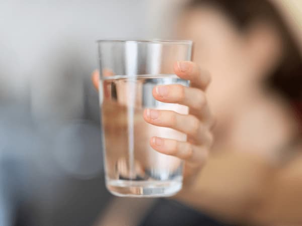 donna che beve acqua per favorire il drenaggio dei liquidi e ridurre la ritenzione idrica